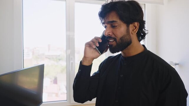 Pakistani Business man in the office. Corporate scene in a modern office with a businessman from pakistan in traditional jubba kandora.