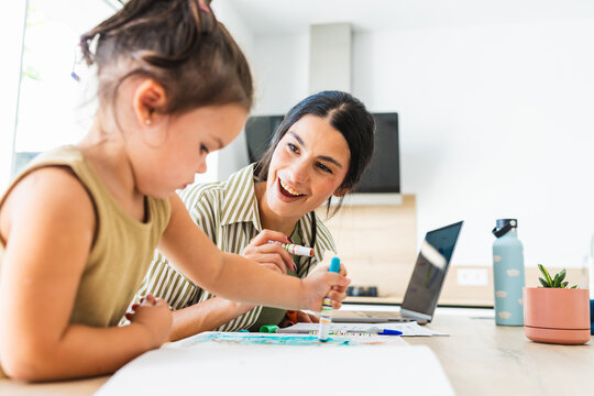 Mother watches her little daughter draw at home