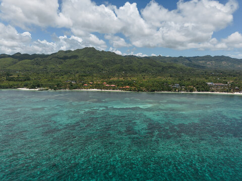 The aerial view reveals a tropical beach and coral reef in Bohol