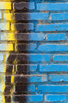 Blue brick wall in Spain with yellow and black weathered paint