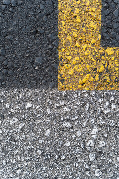 Close-up of asphalt road surface with yellow and white markings