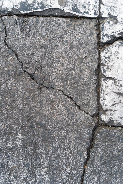 Cracked asphalt pavement with faded road markings in urban Spain