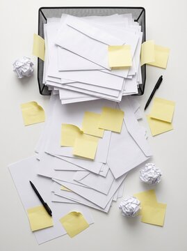 Overflowing inbox tray and sticky notes in vertical overhead view