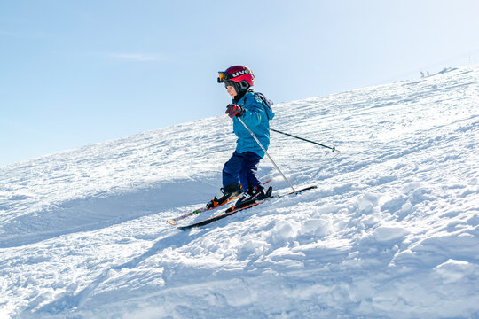 Active kid boy riding downhill,learn skiing in mountains alpine winter resort.little child enjoy extreme sport activities recreation,family luxury vacation