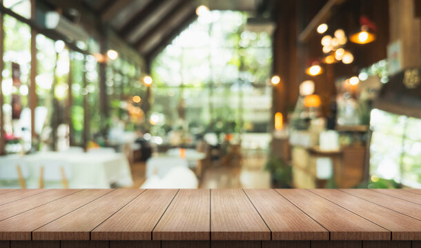 Empty wooden table top with lights bokeh on blur restaurant background.