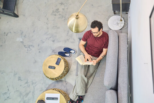 Man relaxing at home reading a book on sofa