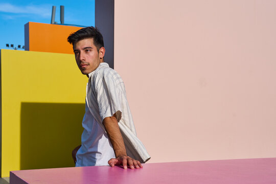 Young man posing near colorful geometric walls