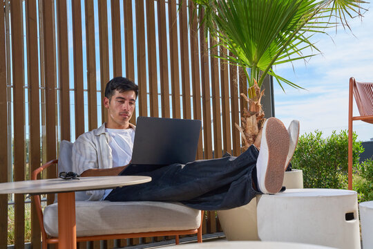 Young man working remotely outdoors using laptop