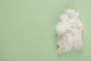 Piece of white cotton wool on pastel green background © Светлана Лазаренко