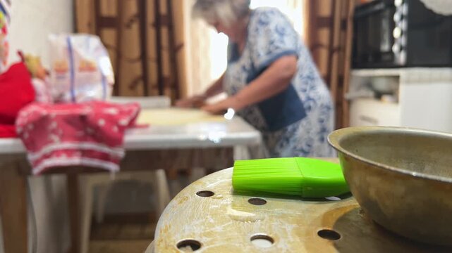 Close-up of elderly woman rolling dough for manti dumplings