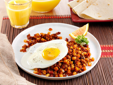 Mexican chorizo, hash with fried egg and orange wedge