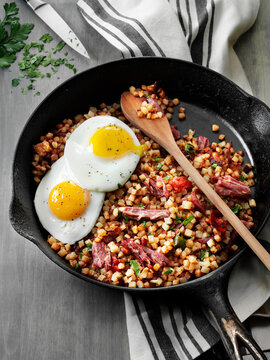 Corned beef hash topped with fried eggs in a cast iron skillet