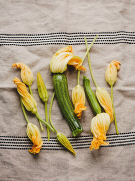 Fresh raw zucchini flowers displayed on linen tablecloth