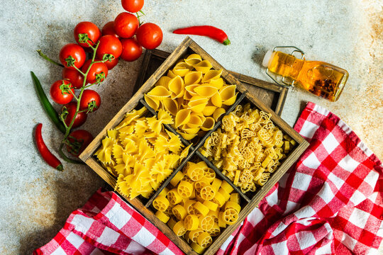 Italian pasta varieties in a Vintage wooden box with tomatoes