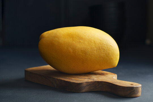 Yellow mango on wooden cutting board