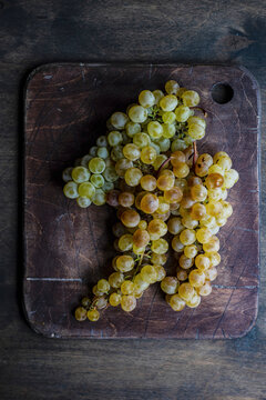 Fresh grape bunches on wooden cutting board in rustic studio setting