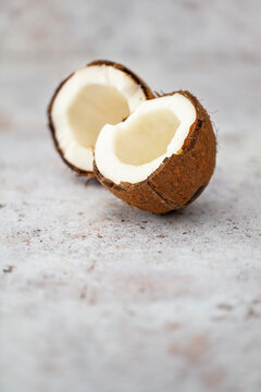 Halved Half a coconut with white flesh on a concrete surface
