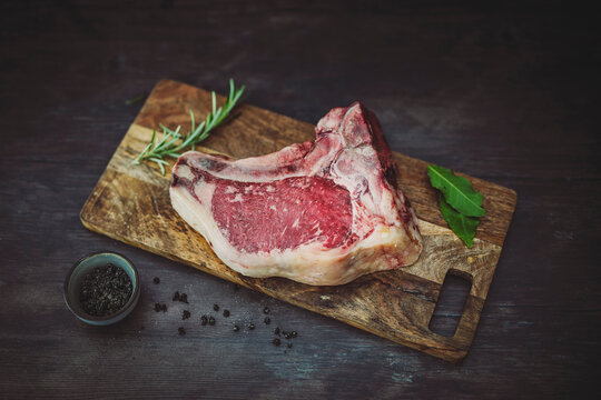 Club dry aged on wooden cutting board with rosemary, bay leaf