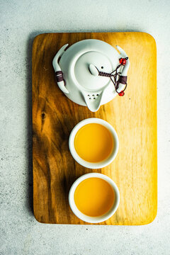 Asian style tea pot with two tea cups on wooden board