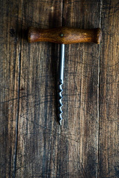 Vintage corkscrew with wooden handle on rustic wood background