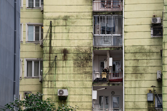 Residential building facade covered in heavy mold and water stains in Batumi, Georgia, weathered apartment house exterior showing unsafe living conditions, water logging and rust due to high humidity.