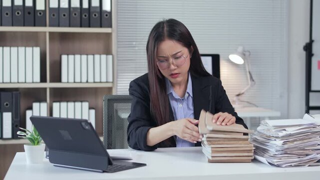 Stressed asian businesswoman searching for documents, feeling frustrated by heavy workload and paperwork in a modern office