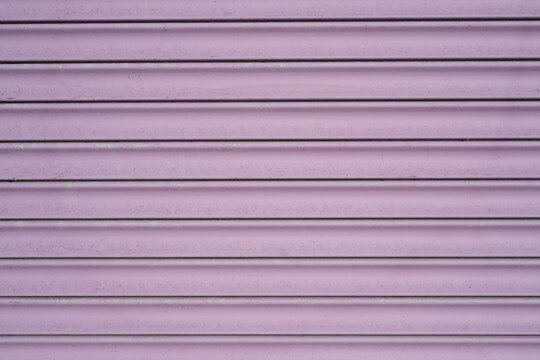 Lilac painted metal roller shutter texture with horizontal slats and subtle weathering