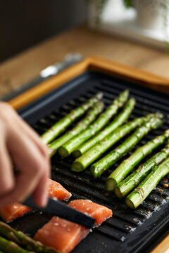 Salmon fillets and green asparagus grilling on a tabletop grill