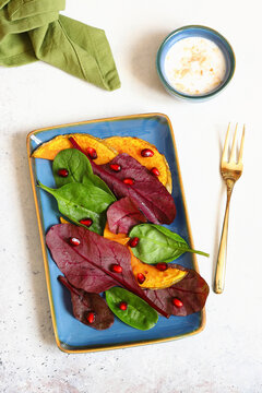 Salad with pumpkin, spinach, red leaf lettuce, and pomegranate seeds