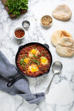 Shakshuka with poached eggs and flatbread in cast iron skillet