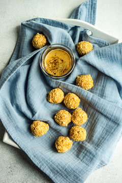 Candies covered with chopped nuts placed on a blue cloth with a glass