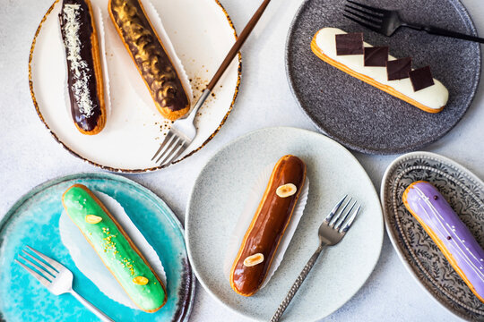 Variety of glazed eclairs with assorted toppings on plates