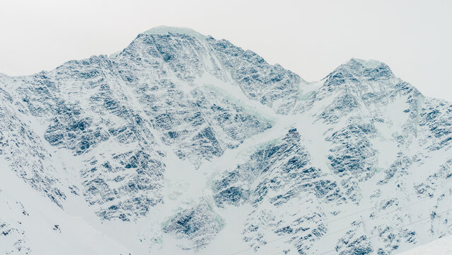Snow-covered Mount Cheget peak in Caucasus Mountains with steep rocky ridges and packed snowfields