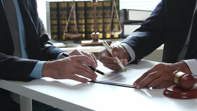Lawyer explaining contract terms to a client before signing the legal document in a law firm office with a gavel and scales
