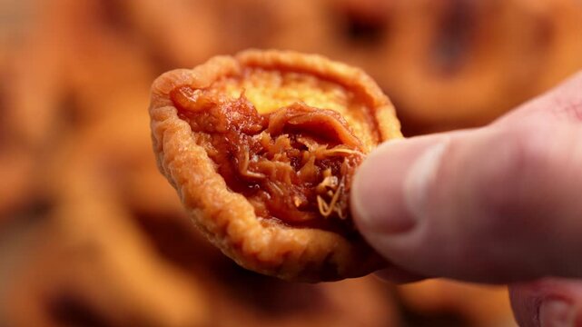Close-up of a hand holding a dried peach half with wrinkled orange flesh and dark interior. Fruit preservation and natural sweet snacks concept