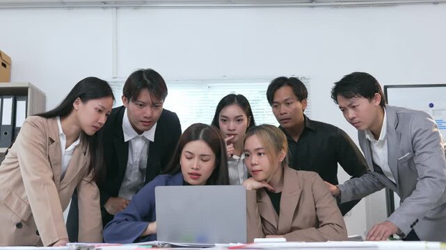 Anxious and stressed Asian office workers showing despair, disappointment, and failure after seeing bad results on their laptop computer