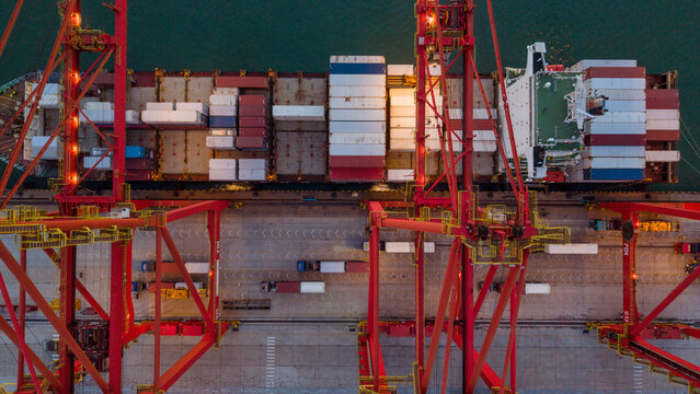 Aerial view of red cranes loading containers on cargo ship at port