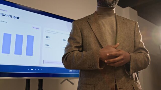 African American middle aged man gesturing while presenting business HR metrics on digital monitor. Footage ideal for corporate management presentations and human resources training videos
