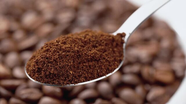 Macro photography A spoon of natural ground coffee, against the background of coffee beans. Coffee. An invigorating drink. The texture of coffee beans. Smooth circular movement