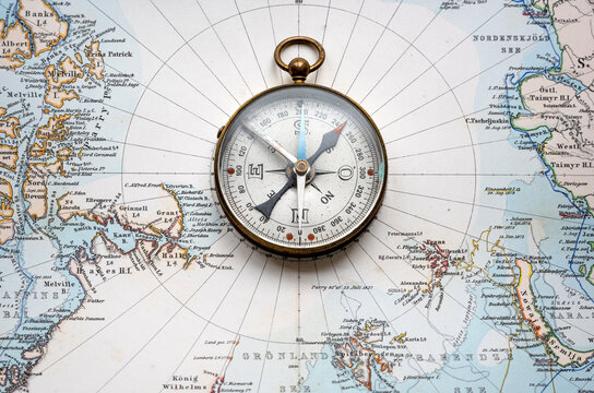 Magnetic old compass on old nord pole map. Travel, geography, history, navigation, tourism and exploration concept background. Retro compass on geography map.