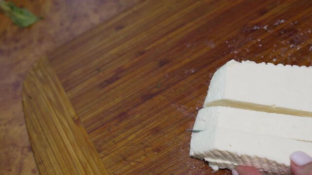Tofu slicing food, preparation of fresh organic white bean curd on a wooden cutting board for a healthy vegetarian recipe at home kitchen