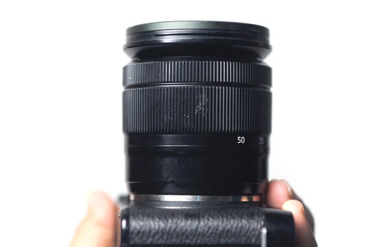 camera lens mounted on a camera body held against a bright white backdrop