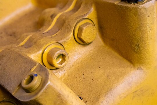 Close up view of hex socket plugs and bolts on yellow machine housing.