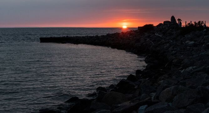 Scenic sunset over the Baltic Sea with a rocky breakwater in the foreground near Kopiec Kaszub&oacute;w (Początek Polski monument) at the tip of the Hel Peninsula, Poland.