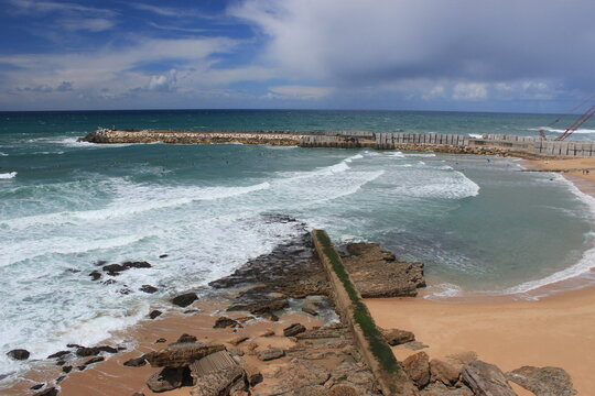Aerial view of a coastal breakwater and sandy beach along the Atlantic ocean in Portugal
