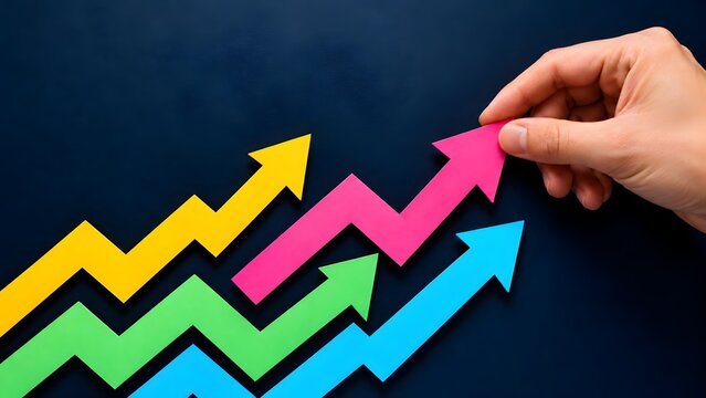Hand adjusting a pink upward trending arrow among a group of colorful zigzag arrows illustrating positive financial market growth and performance tracking
