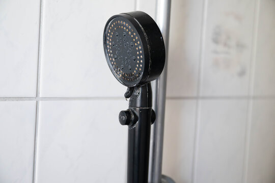 Dirty shower head covered with visible limescale buildup and residue. Bathroom hygiene, hard water deposits, water flow maintenance, and the importance of regular cleaning for a cleaner shower.
