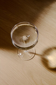 Top View of Champagne Coupe Glass with Sunlight and Shadow on Wooden Table