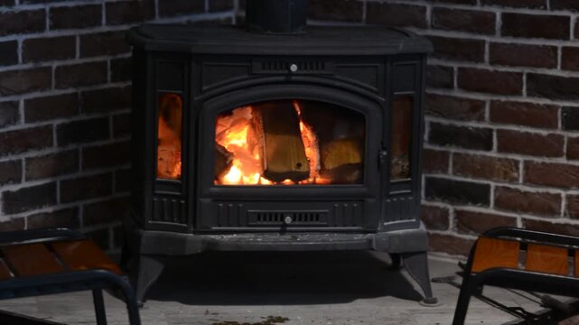 Cozy cast iron wood burning stove with bright burning fire and glowing logs in a rustic room