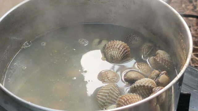 Fresh clams are boiled with garlic and aromatic herbs in a pot. This cooking process enhances rich flavors while removing unwanted fishy odors.